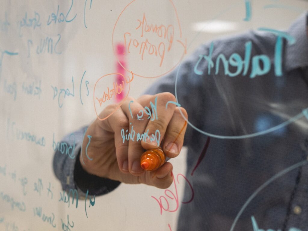 A man writing on a whiteboard, illustrating concepts related to an AI enablement platform tool.